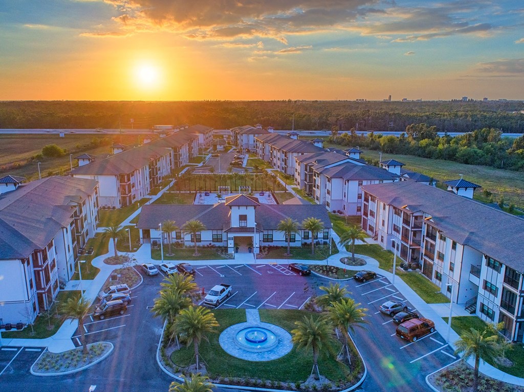 an aerial view of an apartment complex with a sunset in the background