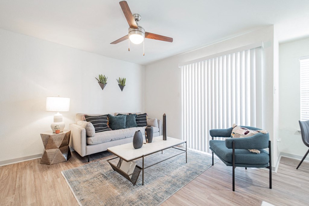 A living room with a couch, chair, and a ceiling fan.