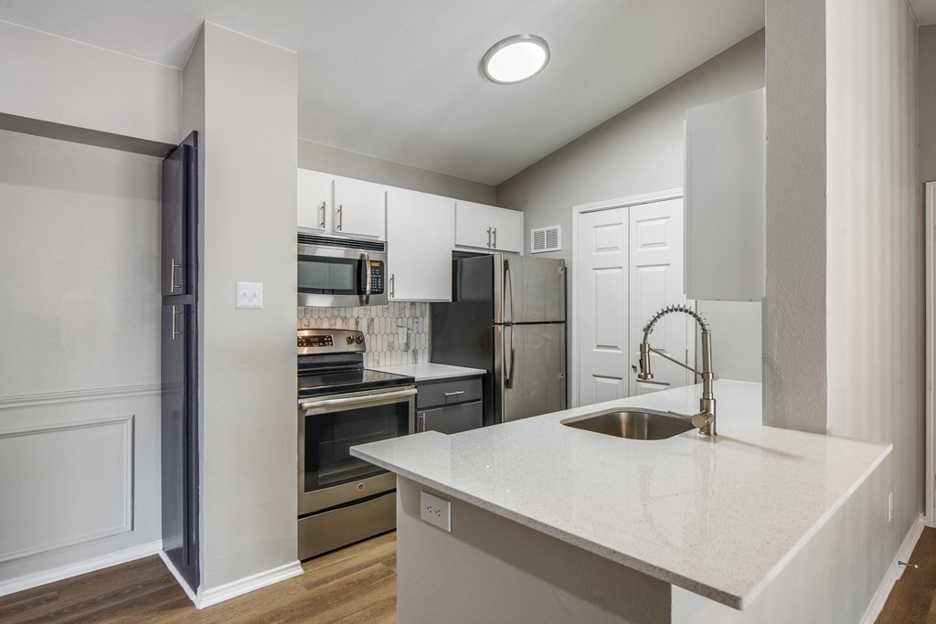 a kitchen with white cabinets and stainless steel appliances