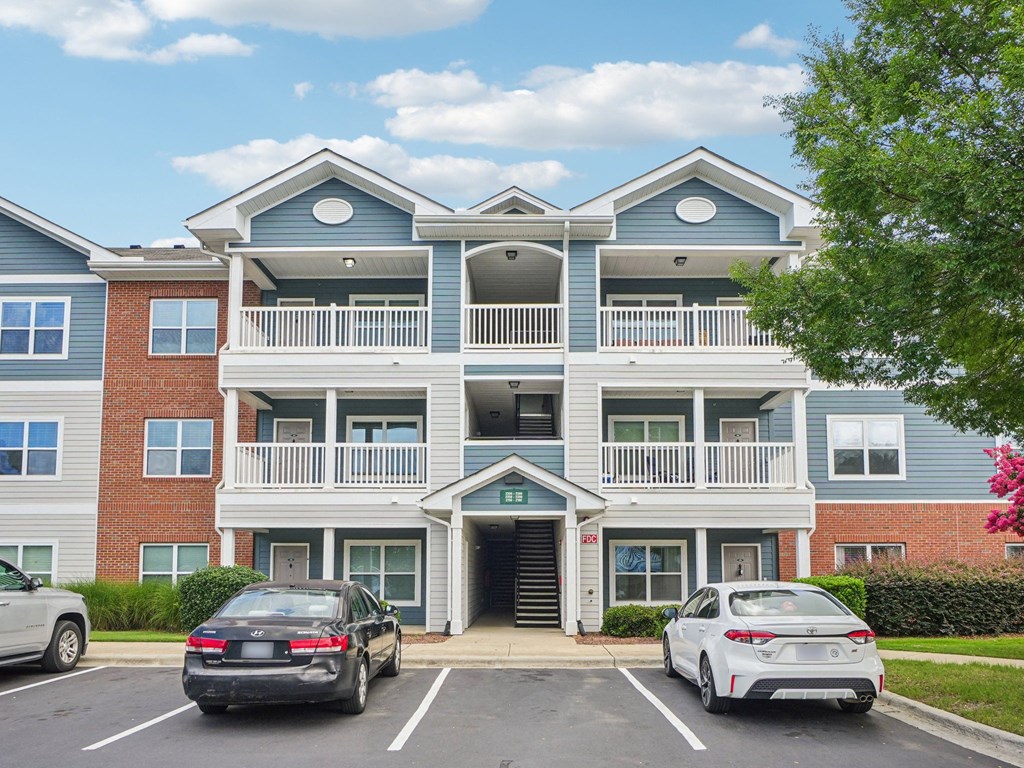 A black car is parked in front of a blue and red building.