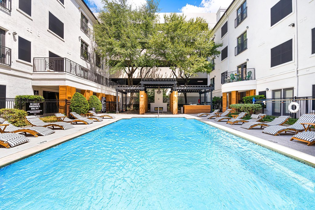 a swimming pool with chaise lounge chairs in front of an apartment building