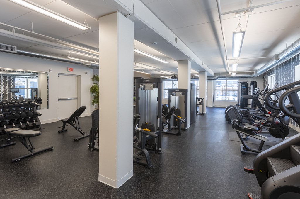 A gym with a variety of equipment including treadmills, weights, and exercise machines.