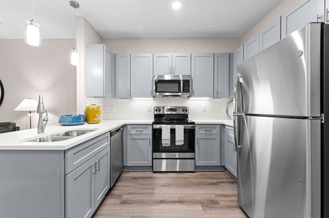 an empty kitchen with stainless steel appliances and gray cabinets