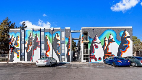 a building with graffiti on the side of it and cars parked