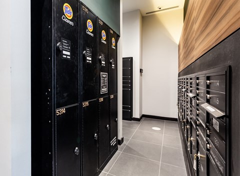 a row of black industrial lockers in a room with a wall of wooden cabinets