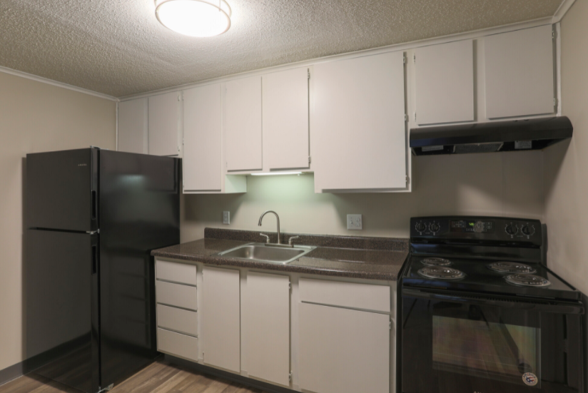 a kitchen with white cabinets and black appliances