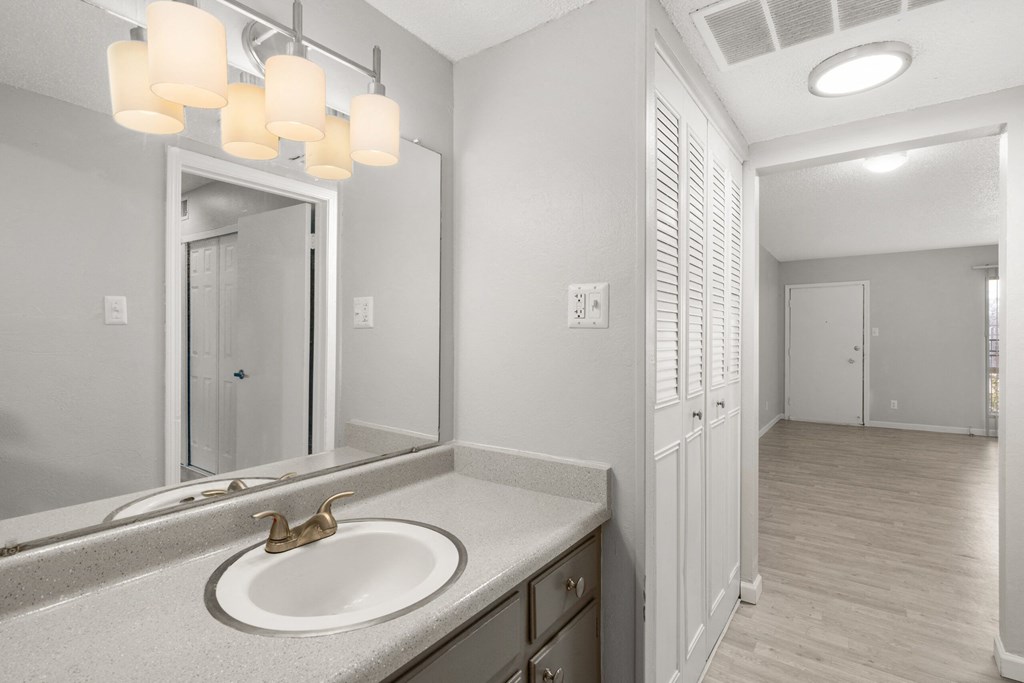 a bathroom with a sink and a mirror and a hallway