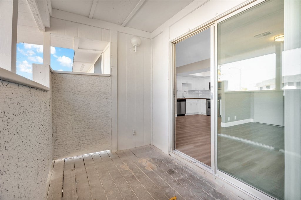 an empty room with a sliding glass door and a kitchen in the background