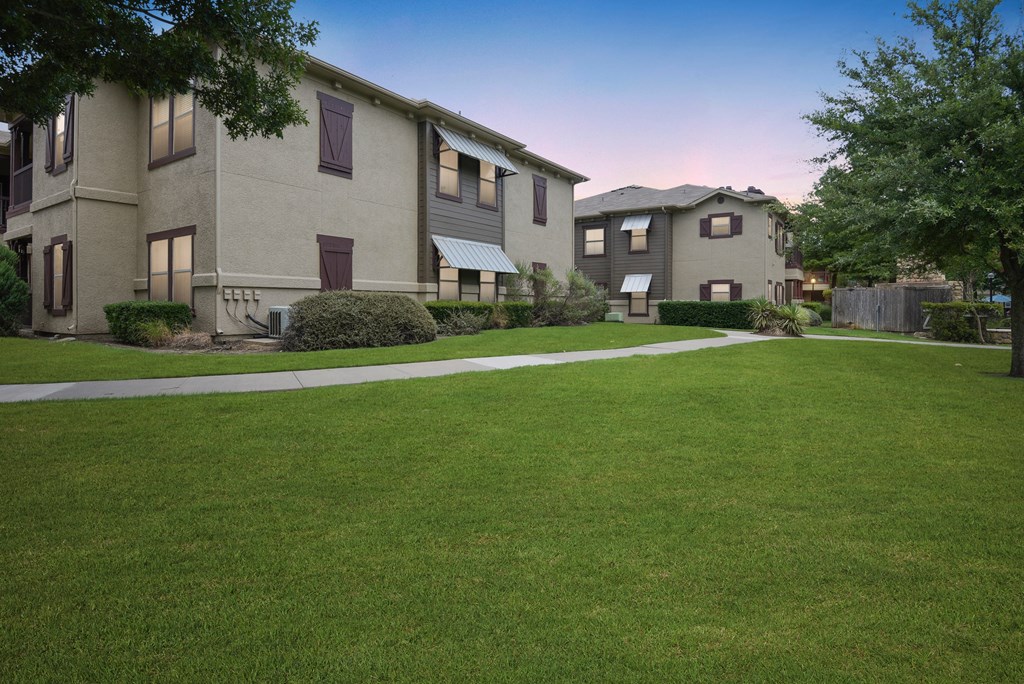 an image of an apartment complex with a green lawn