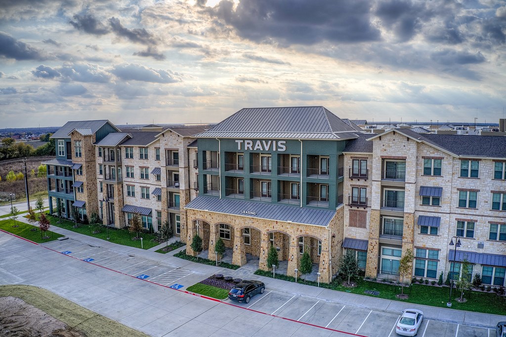 an aerial view of a large apartment building with a parking lot in front of it