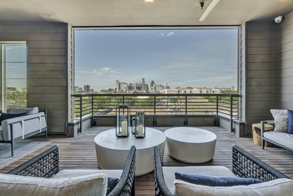 A balcony with a table and chairs overlooking a city skyline.