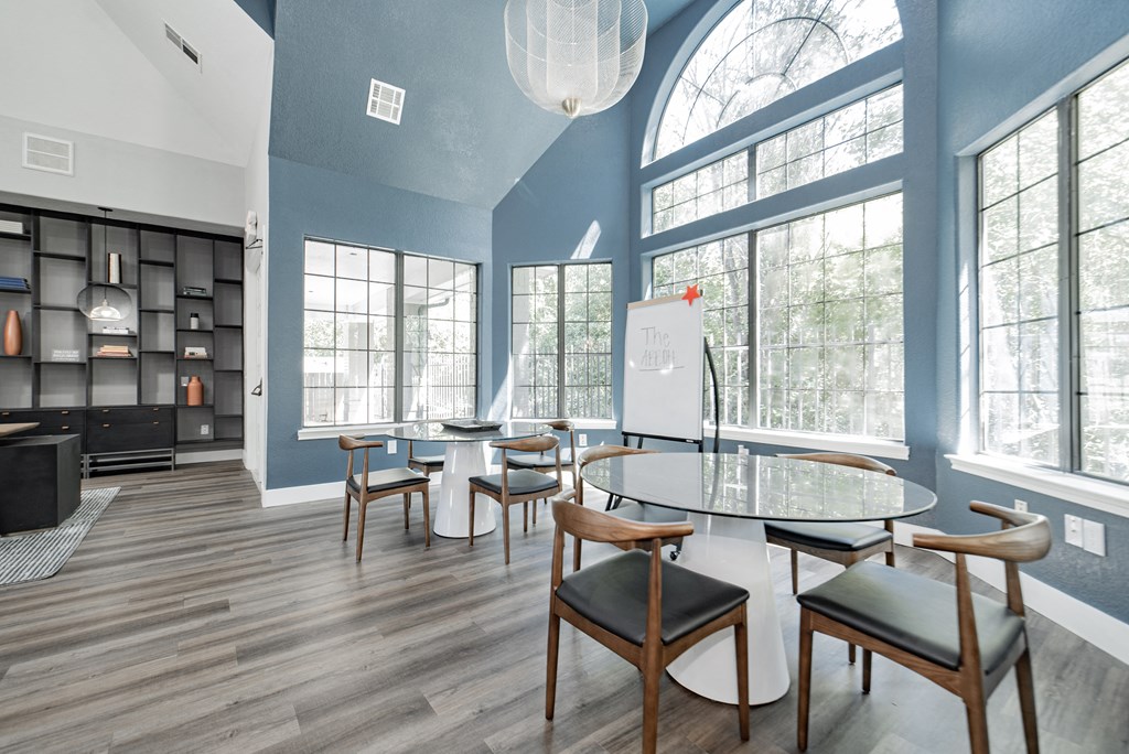 a dining room with a table and chairs and large windows