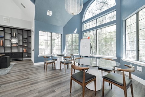 a dining room with a table and chairs and large windows