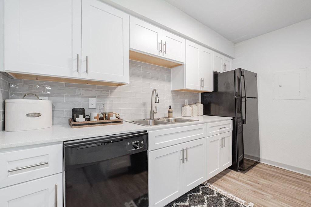 A kitchen with white cabinets and a black refrigerator.