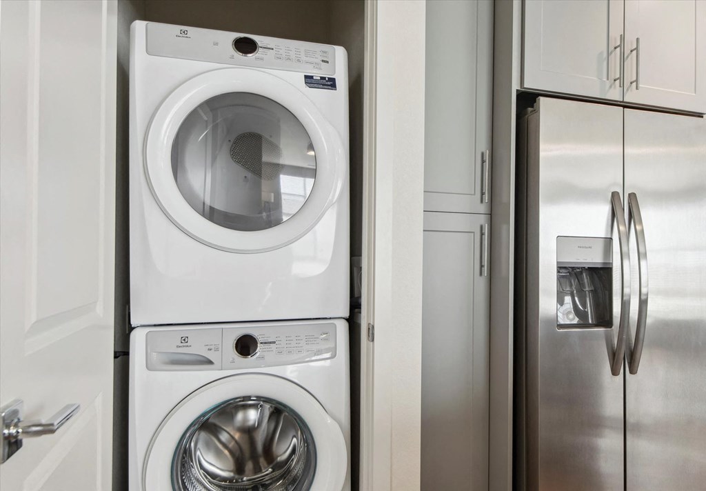 A white washing machine and dryer stacked on top of each other in a laundry room.