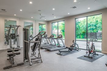 A spacious gym with a variety of equipment including treadmills, stationary bikes, and weight machines.