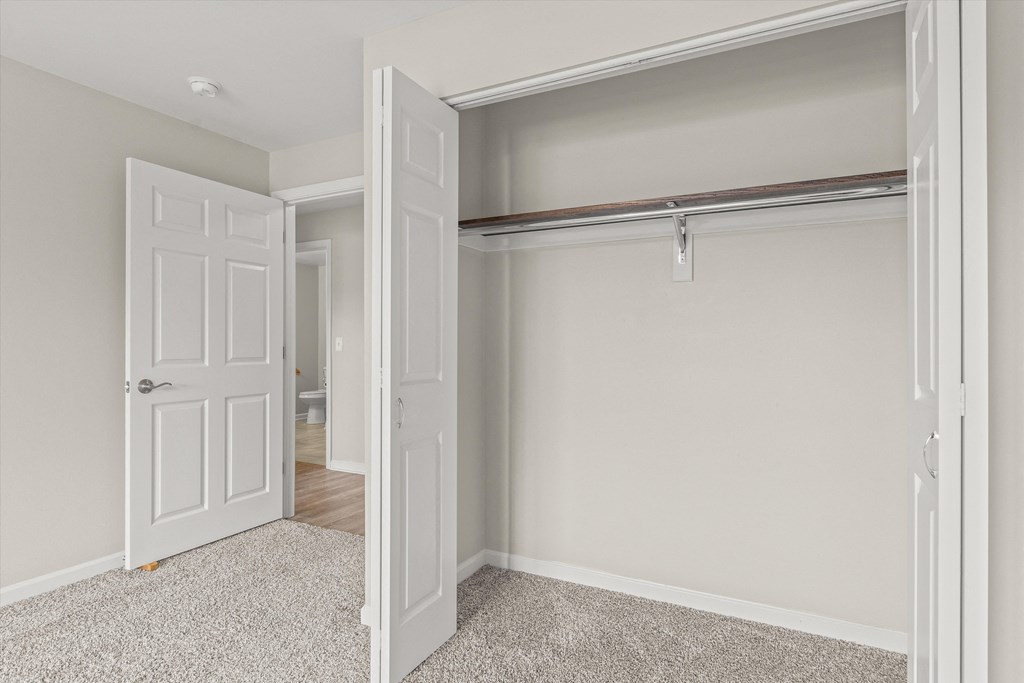 an empty bedroom with an open closet and a door to the bathroom