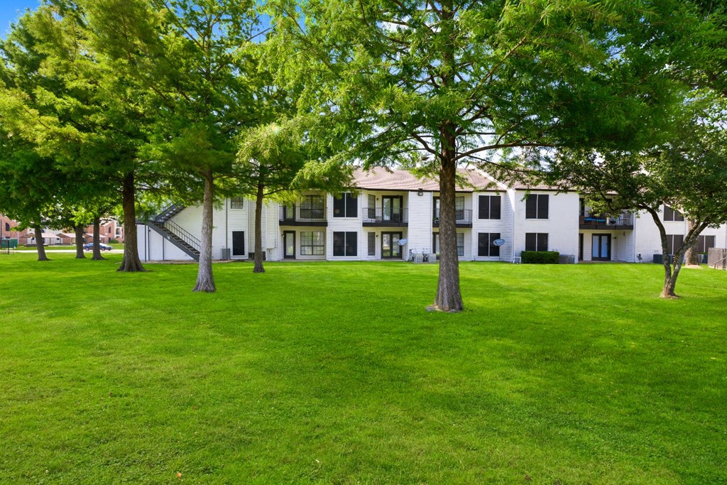 a grassy area with trees in front of a building