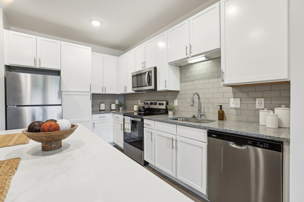 A modern kitchen with white cabinets and stainless steel appliances.