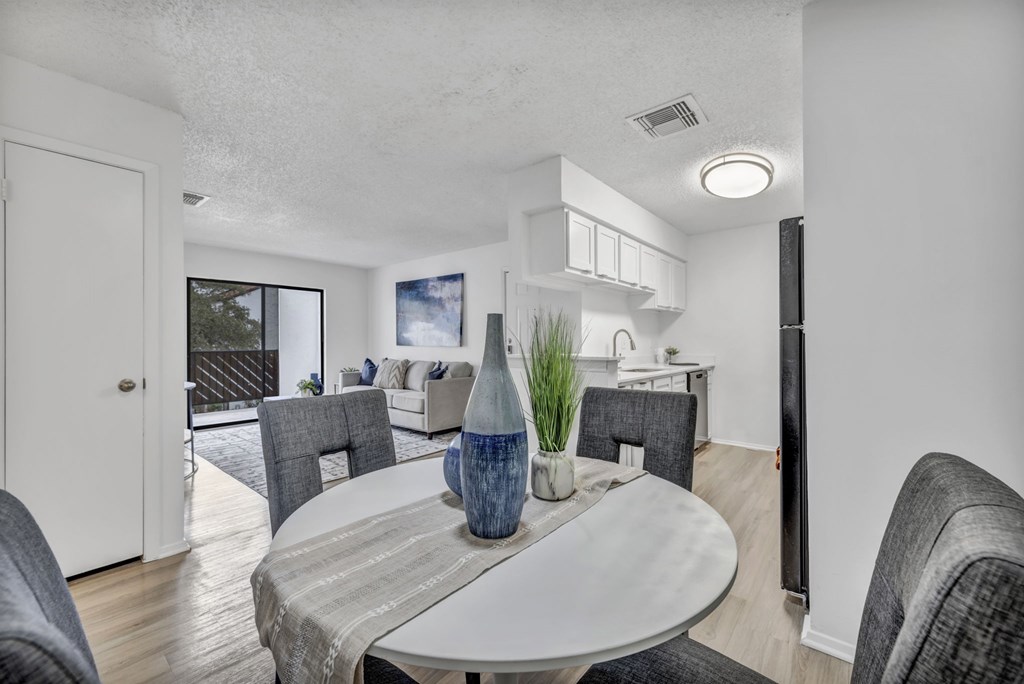A modern dining room with a round table and grey chairs.