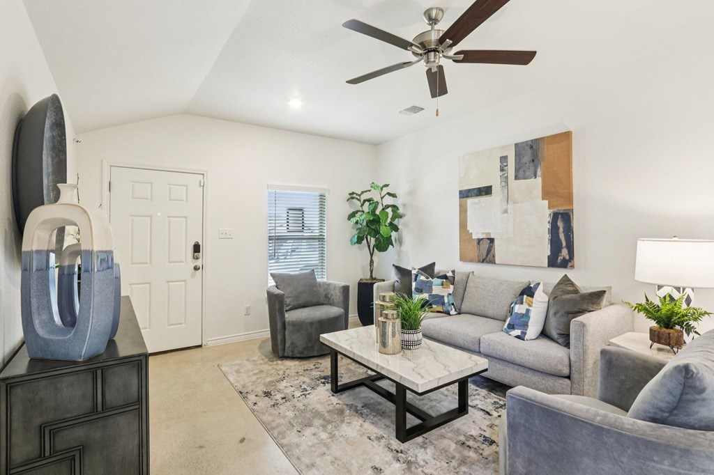 A living room with a grey couch, a coffee table, and a ceiling fan.