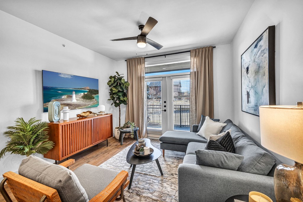 a living room with a gray couch and a ceiling fan
