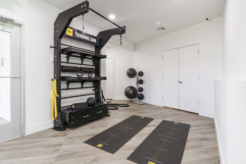 a home gym with weights and equipment in a white room