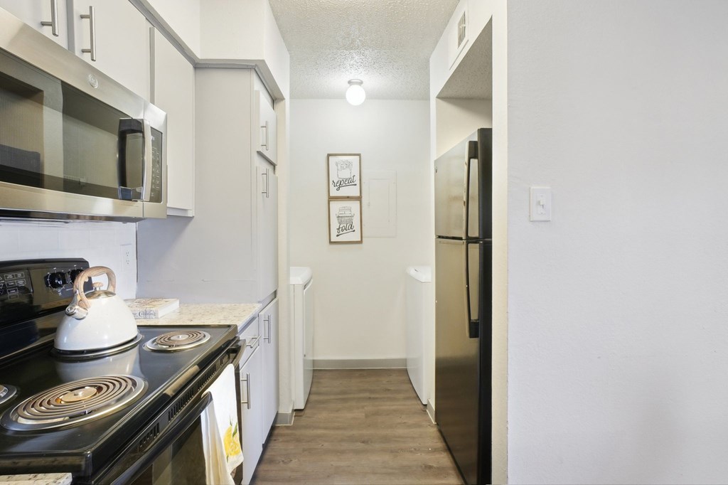 A kitchen with a black stove top oven and a black microwave above it.