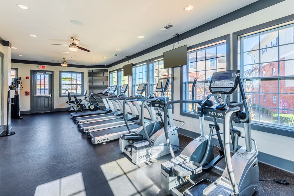 a gym with cardio equipment and windows