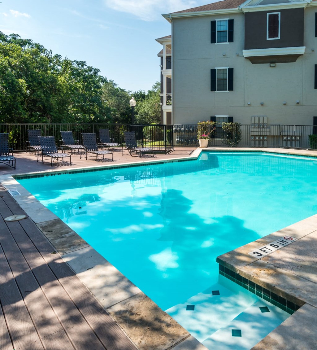 a resort style pool with chairs and a building in the background