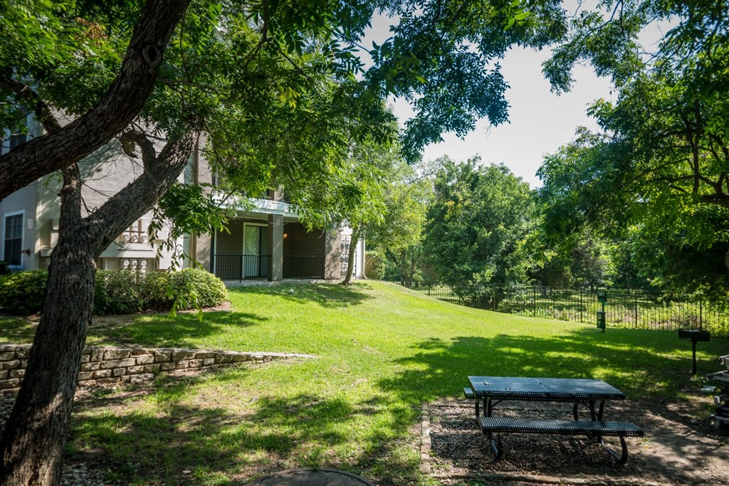 a picnic table under a tree in front of a house