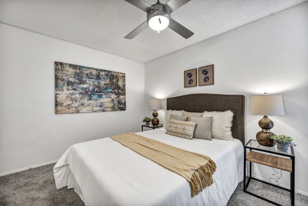 A bedroom with a large bed and a ceiling fan.