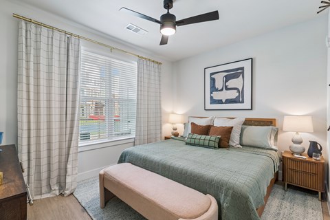 A bedroom with a bed, nightstand, and window with curtains.