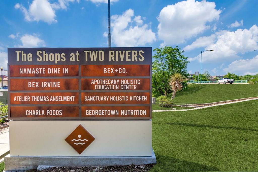 a sign for the shops at two rivers at the entrance of a park