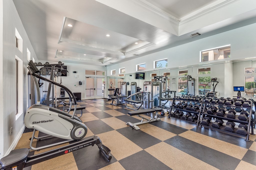 a gym with weights and cardio equipment on a checkered floor