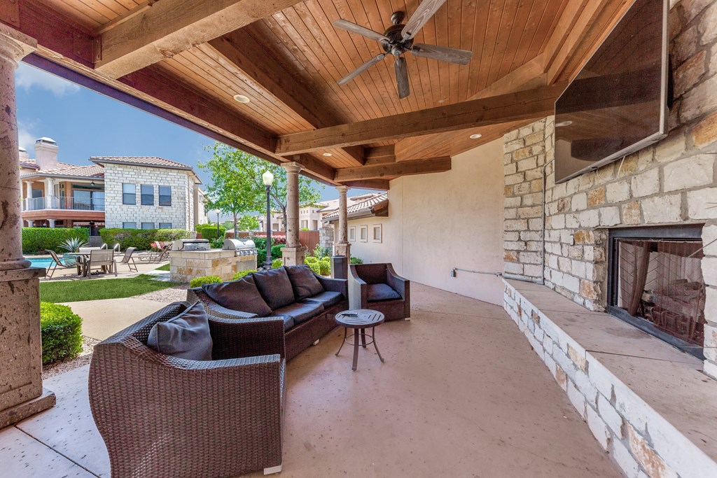 a covered patio with couches and a fireplace