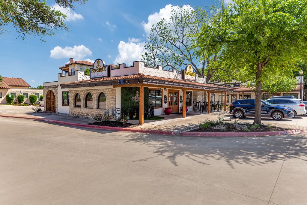 the front of a restaurant with a parking lot and trees