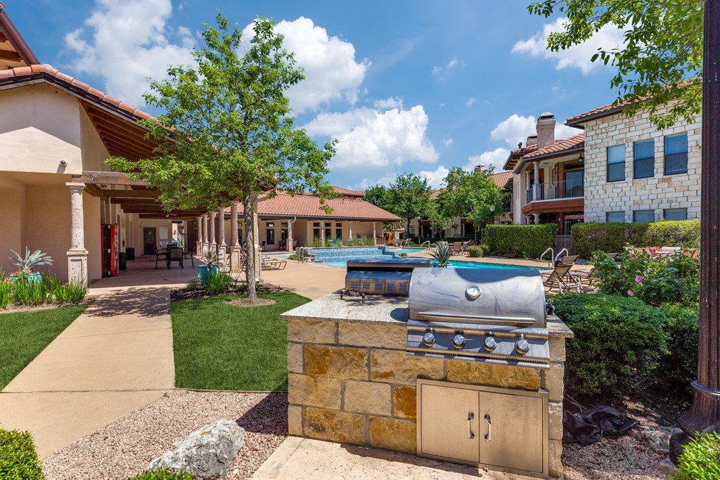 a barbecue grill in the backyard of a house with a swimming pool