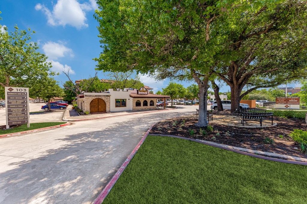 a park with trees and a building on the side of a street