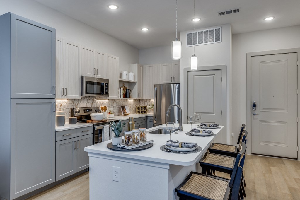 an open kitchen and dining area with white cabinets and stainless steel appliances