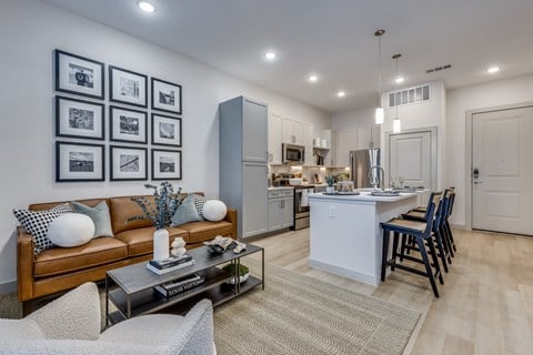 a living room with a couch and a table in front of a kitchen