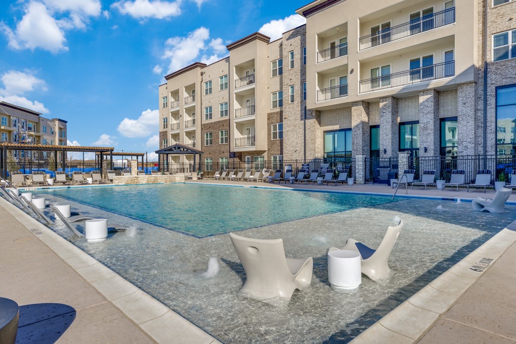 a swimming pool with chairs and a building in the background