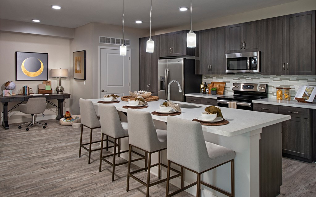 a kitchen with a large center island with a white counter top and chairs