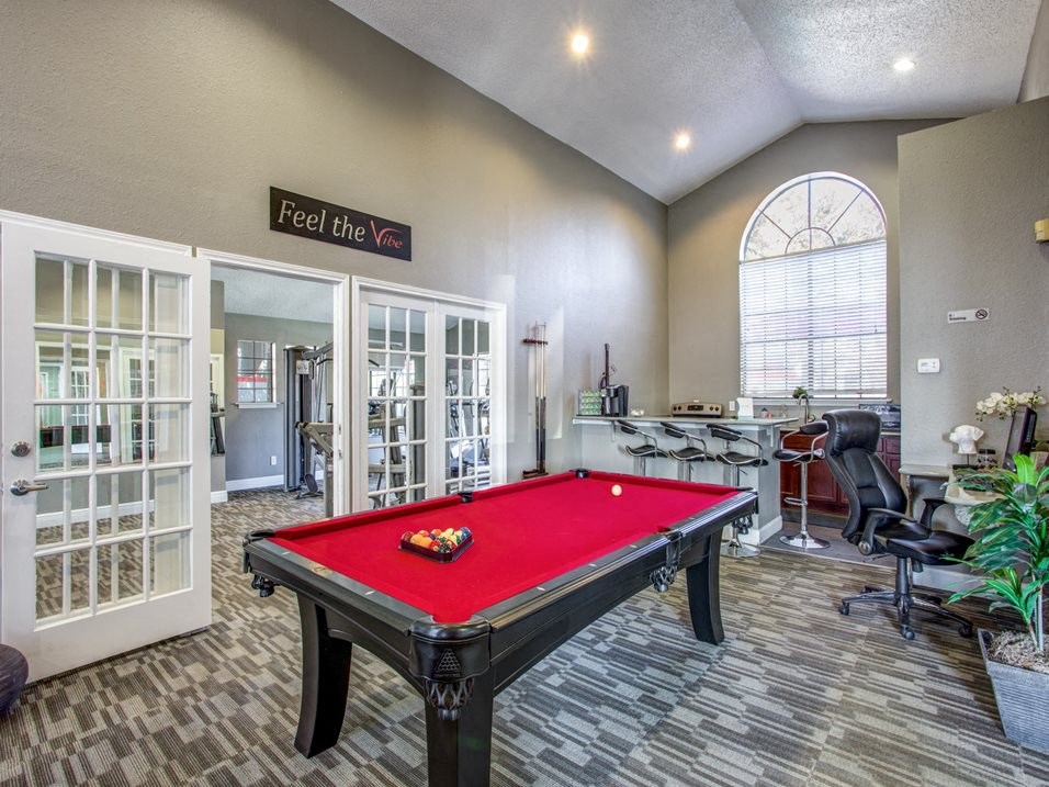 a game room with a red pool table and a bar