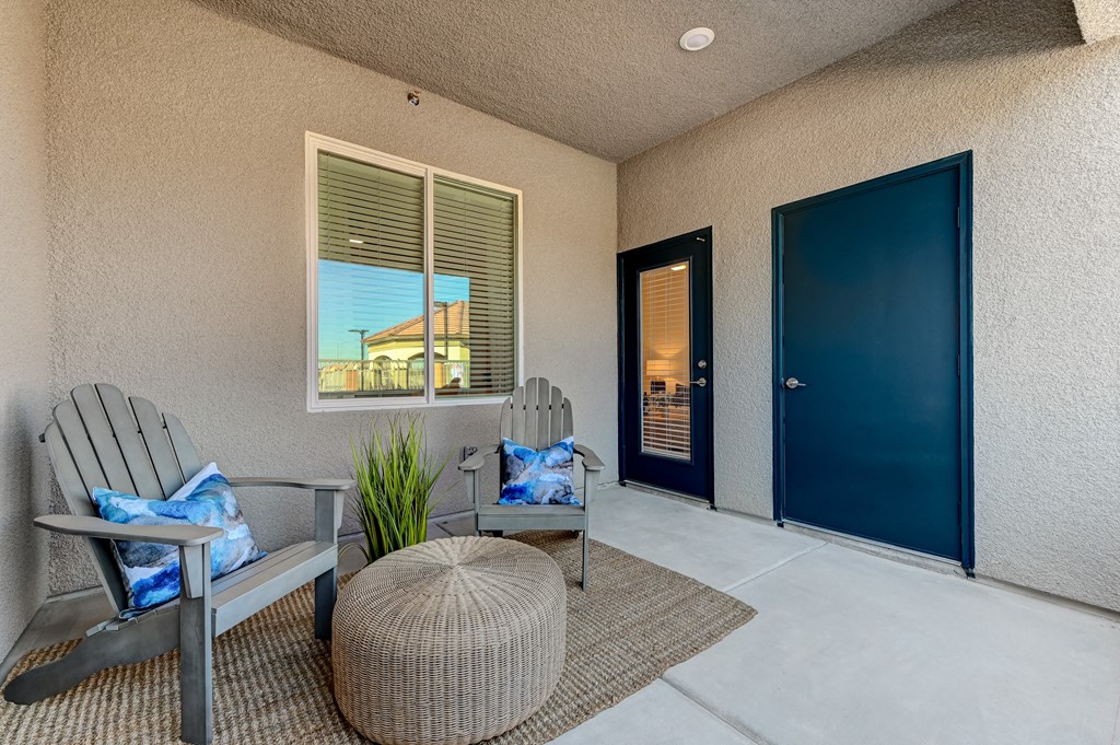 the front porch of a condo with two rocking chairs and a blue door