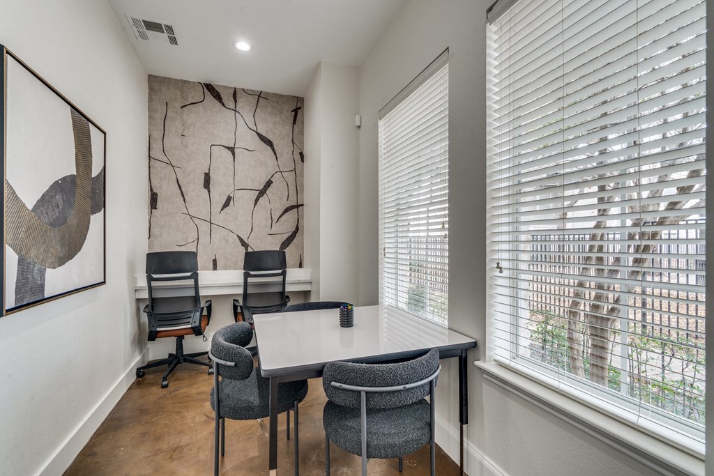 an office with a table and chairs and two windows