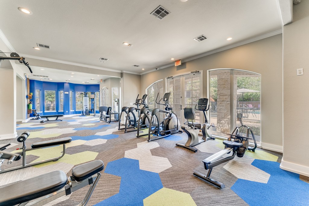 a gym with cardio machines and weights on the floor at the community center