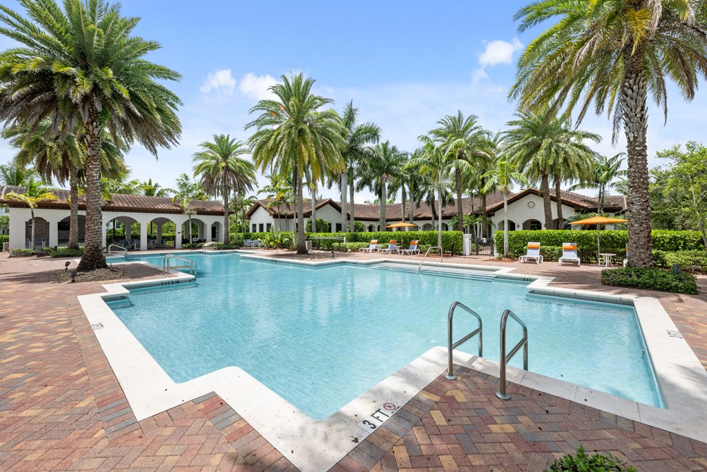 a large swimming pool with palm trees in front of a house