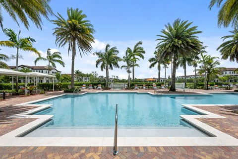 a swimming pool with palm trees in front of a hotel