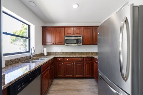 A kitchen with a stainless steel refrigerator and wooden cabinets.